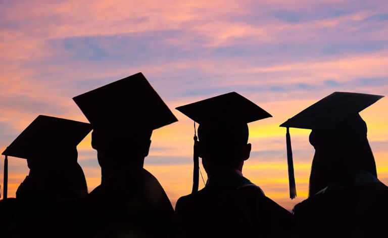 Image showing silhouettes of graduates wearing caps and gowns with a sunset in the background