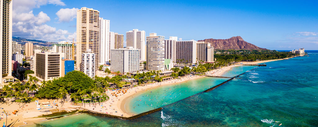 A view of Waikiki Beach with high rises and palm trees in the background in Honolulu, Hawaii