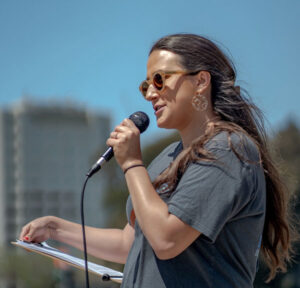 Julia Rose Dowell speaks into a microphone during a public event