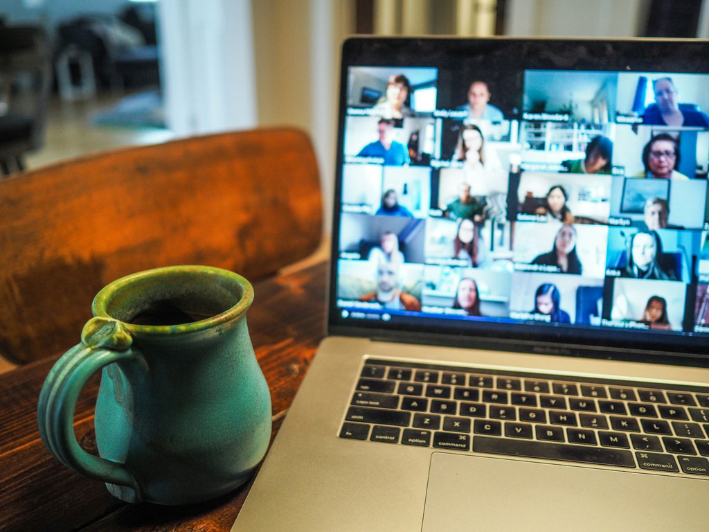 Laptop screen with images of many participants in a virtual session.