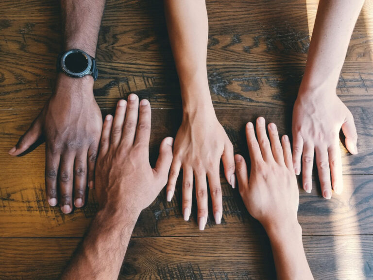 Diverse group of hands lined up on a table, Credit: Clay Banks, Unsplash