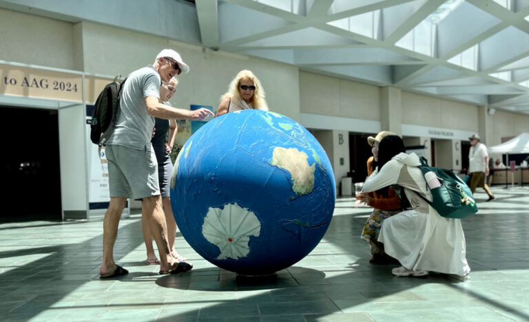 AAG annual meeting attendees interact with AAG's giant inflatable globe during a break in the conference.